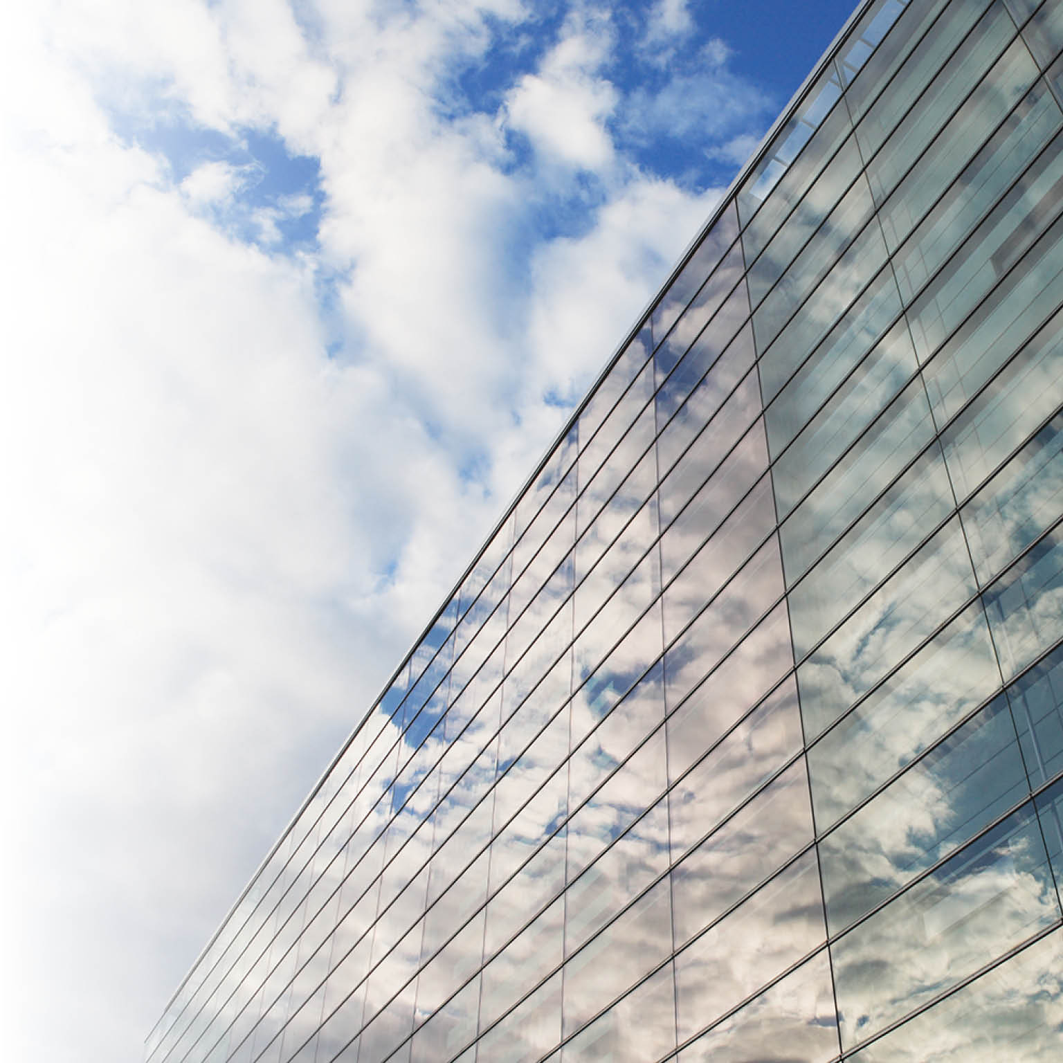 Sky and glass wall of an office building  reflections of clouds 