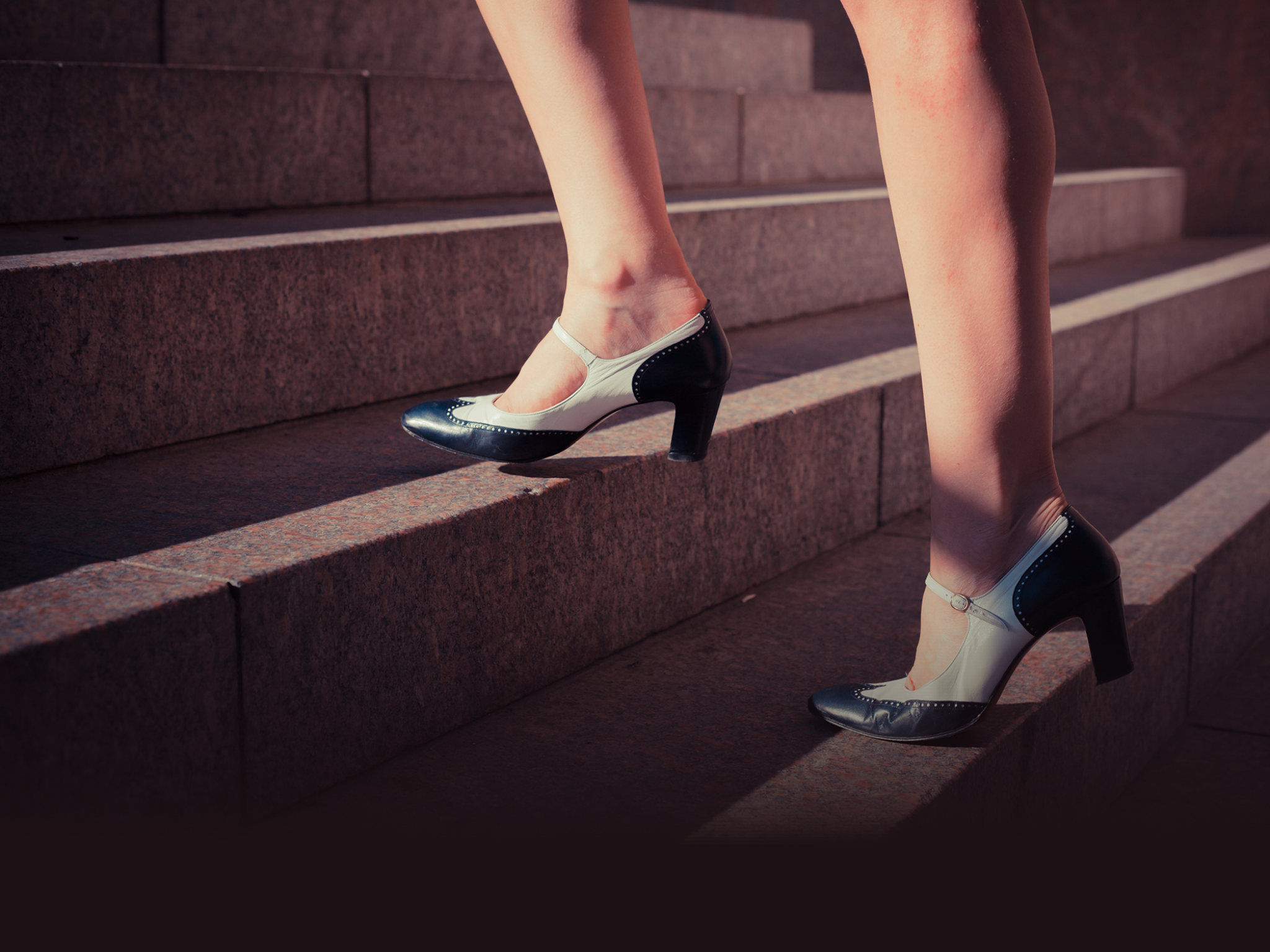 A young woman is walking up some stairs outside on a sunny day in the city