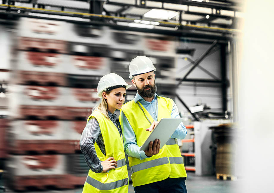A portrait of a mature industrial man and woman engineer with tablet in a factory  working 
