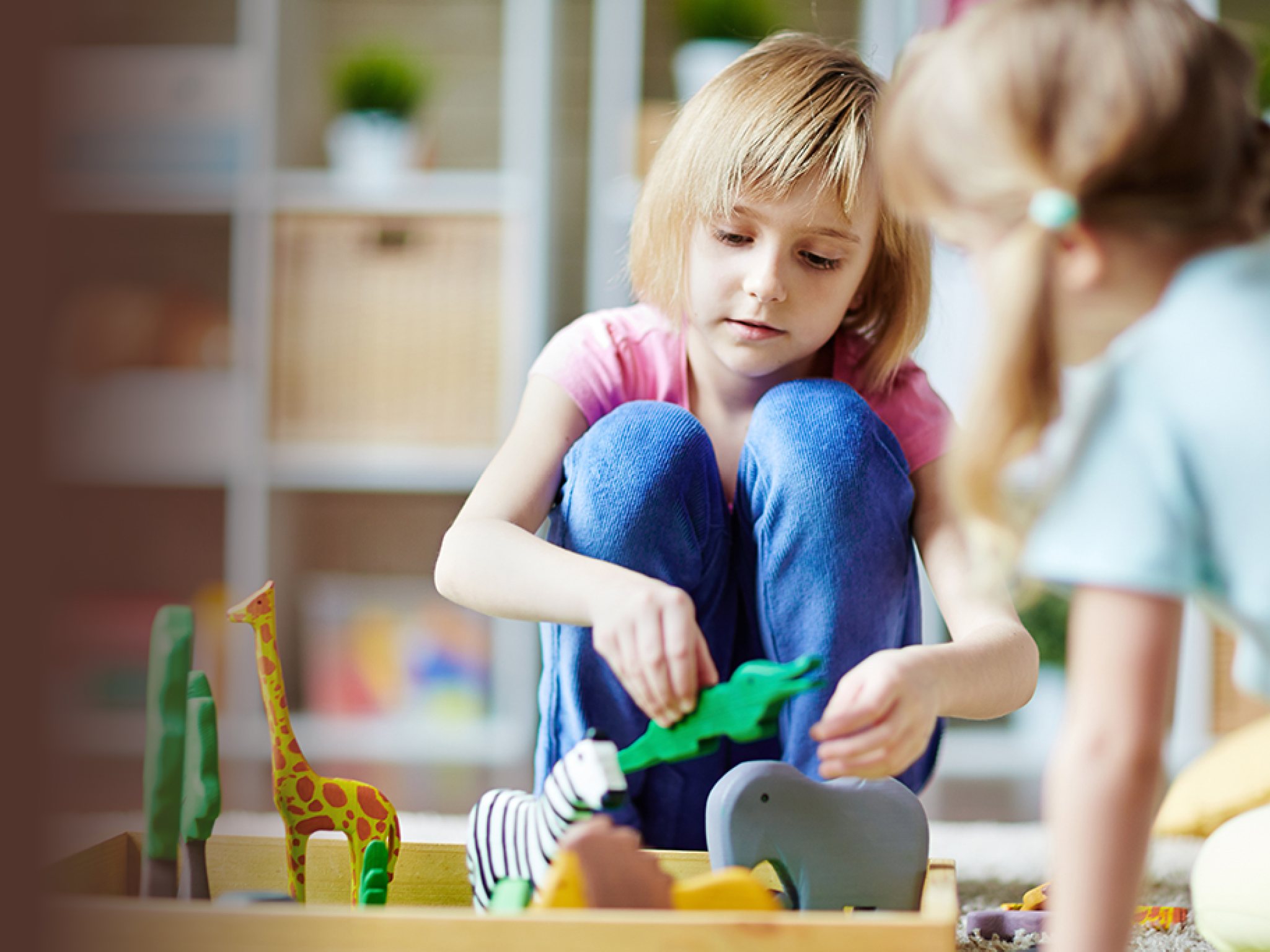 Cute girls playing with toy animals in kindergarten