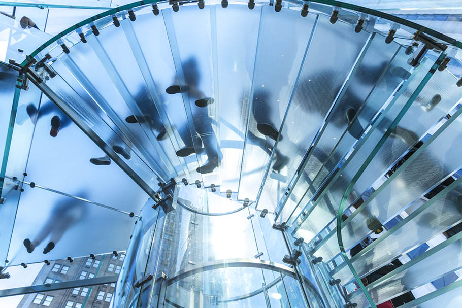 Low angle view of people walking on transparent spiral staircase 