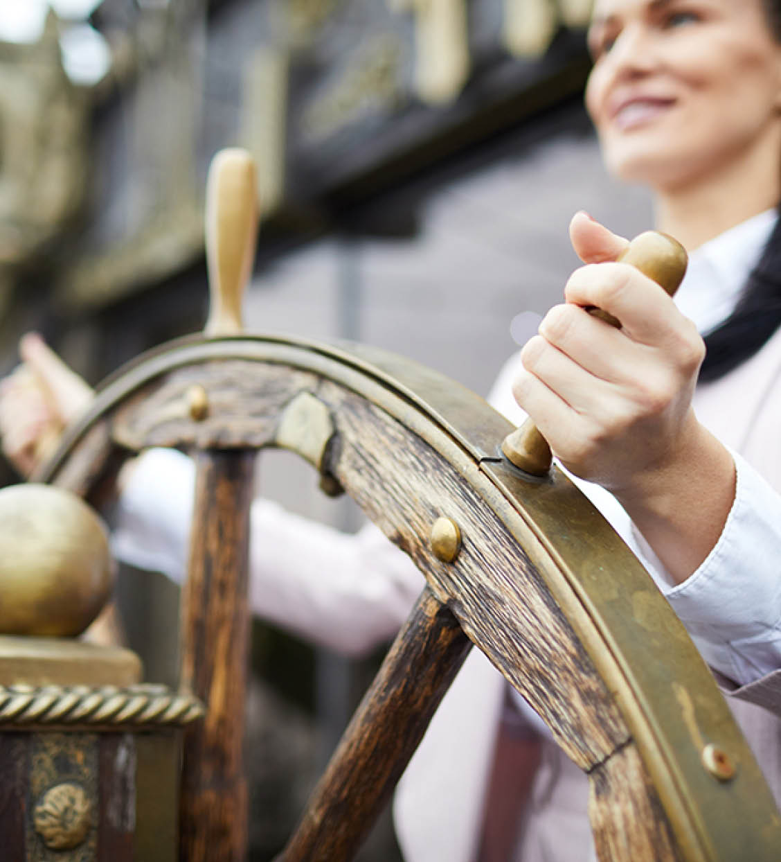 Hand of young successful businesswoman turning sailing wheel while leading large ship